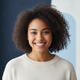Close-up portrait of a smiling young woman with diverse features, looking directly at the camera.